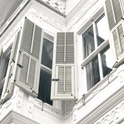 Capture of a white building facade with open shutters, showcasing classic architectural design.