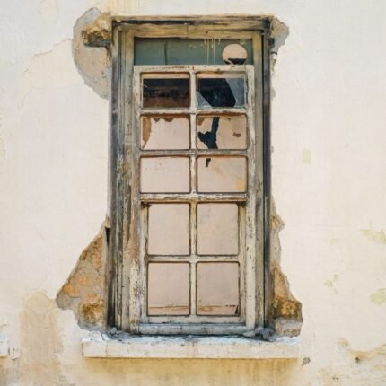 An old wooden window set in a weathered wall, showcasing rustic decay.