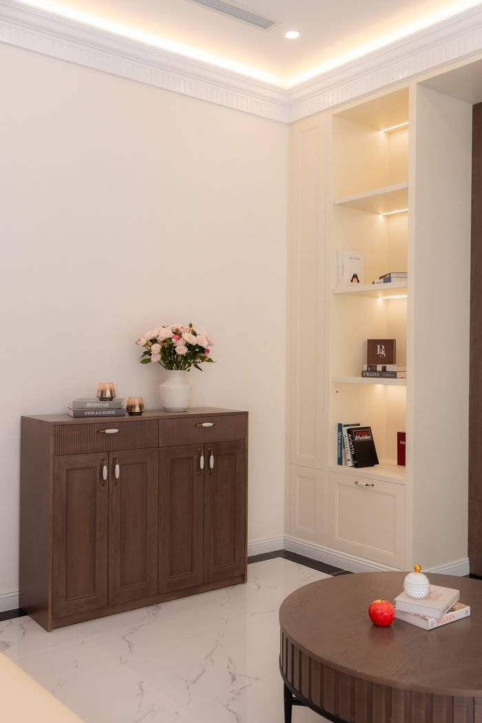 A stylish modern room with wooden furniture and cozy lighting, featuring bookshelves and decorative items.