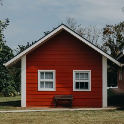A vibrant red bungalow facade with windows and a bench in a serene outdoor setting in the Philippines.